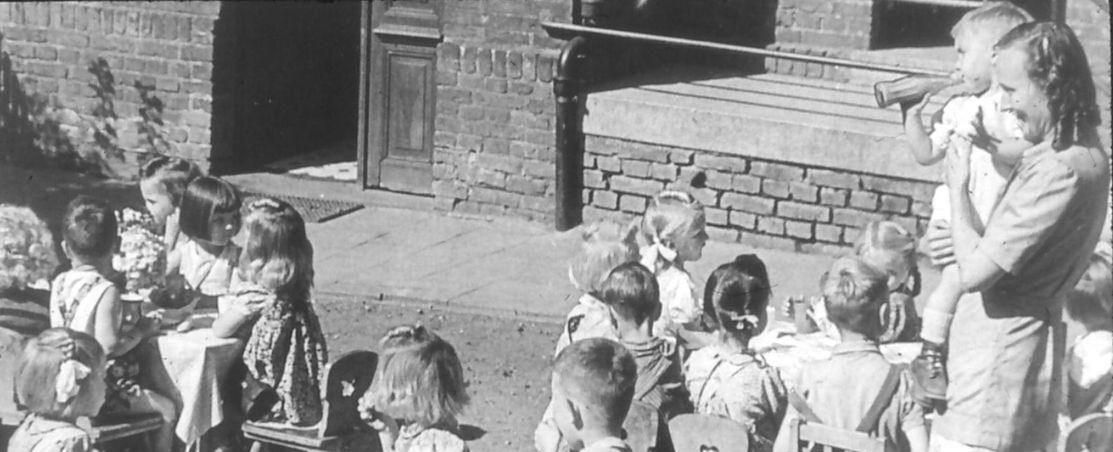 Ein altes Schwarz-weiß-Bild von einer Gruppe von Kindern mit Erzieherin